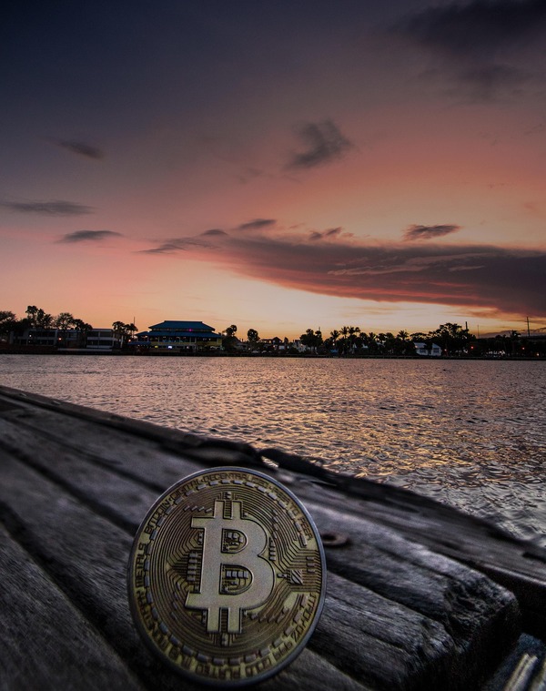 Bitcoin coin resting on a dock at sunset