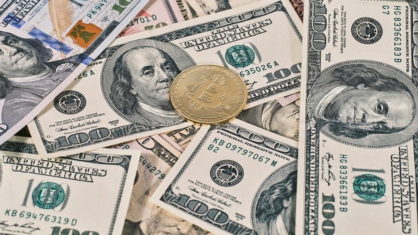 Bitcoin coin placed on top of US dollar banknotes