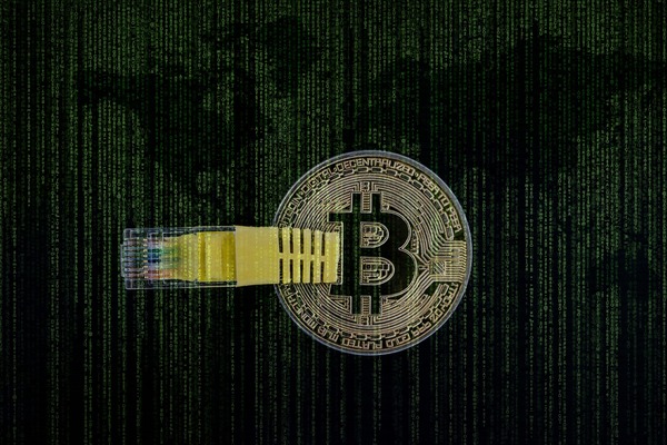 Bitcoin coin connected to a network cable against a digital world map background