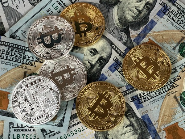 Multiple gold and silver Bitcoin coins scattered on US dollar banknotes