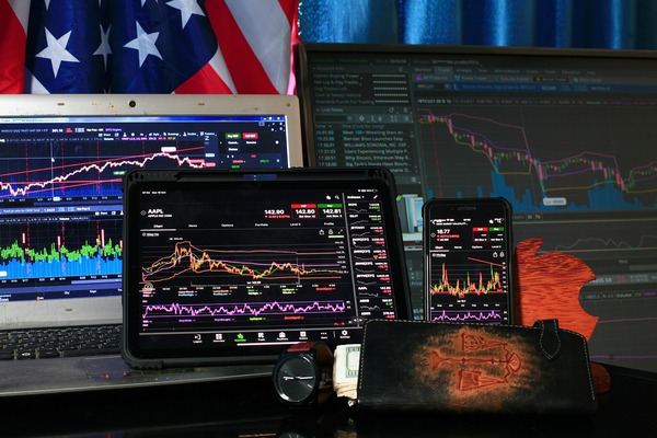 Multiple trading screens showing stock charts alongside a wallet and cash