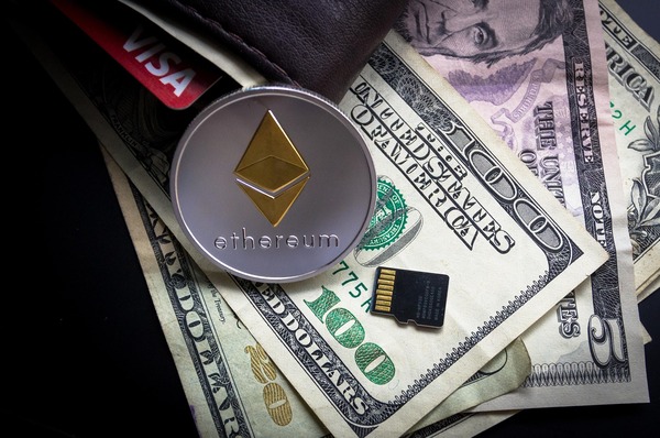 Ethereum coin resting on a leather wallet with cash and credit cards