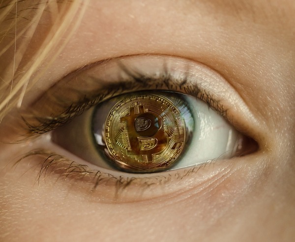 Close-up of an eye with a Bitcoin coin reflected in the iris
