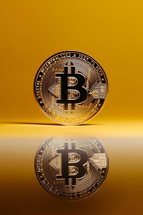 Gold Bitcoin coin standing upright with a reflective mirror surface