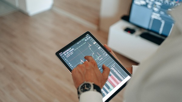 Hands holding a tablet showing a cryptocurrency price chart