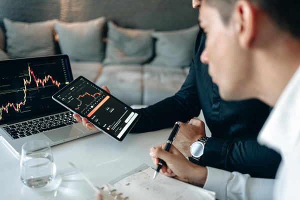 Traders reviewing a cryptocurrency price chart on a laptop and phone